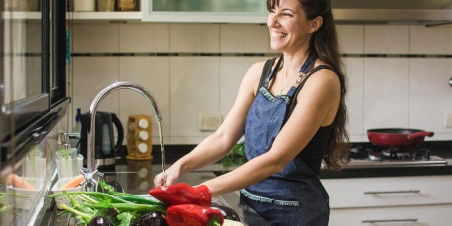 A person smiles while preparing a meal in their kitchen.